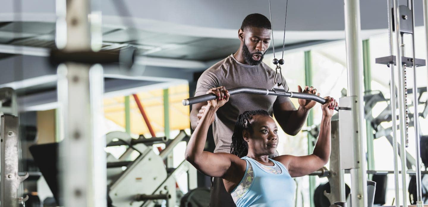 Personal trainer helping client at gym