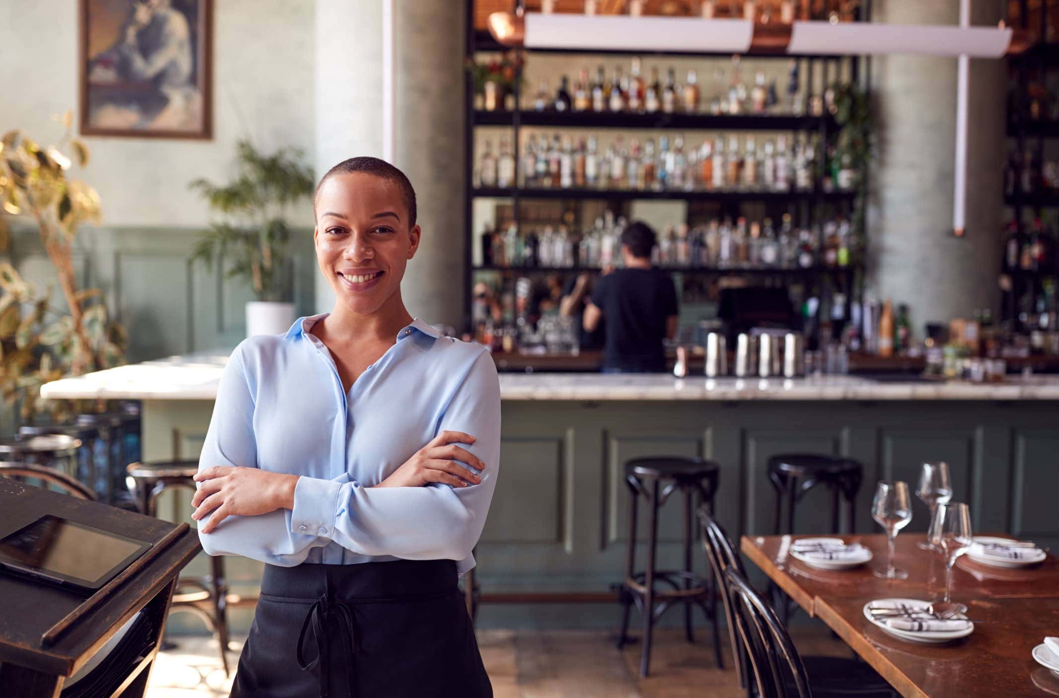 Confident Female Owner Of Restaurant Bar Standing By Counter