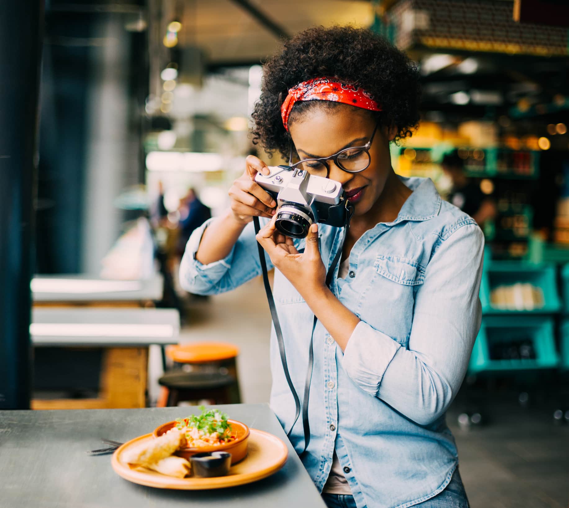 Young woman taking photos of her food with a vintage slr camera