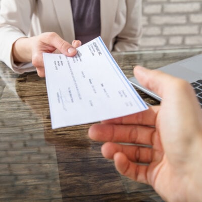 Businesswoman Giving Cheque To Her Colleague