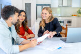 Couple sitting in a kitchen with a tax preparer going over their documents