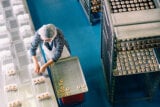 Woman placing cookies in packaging in bakery workshop.