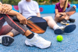 Woman holding pickelball racket while talking with friends