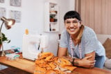Cropped shot of a young woman stitching fabric using a sewing machine at home.