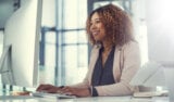 Smiling woman works at computer in office