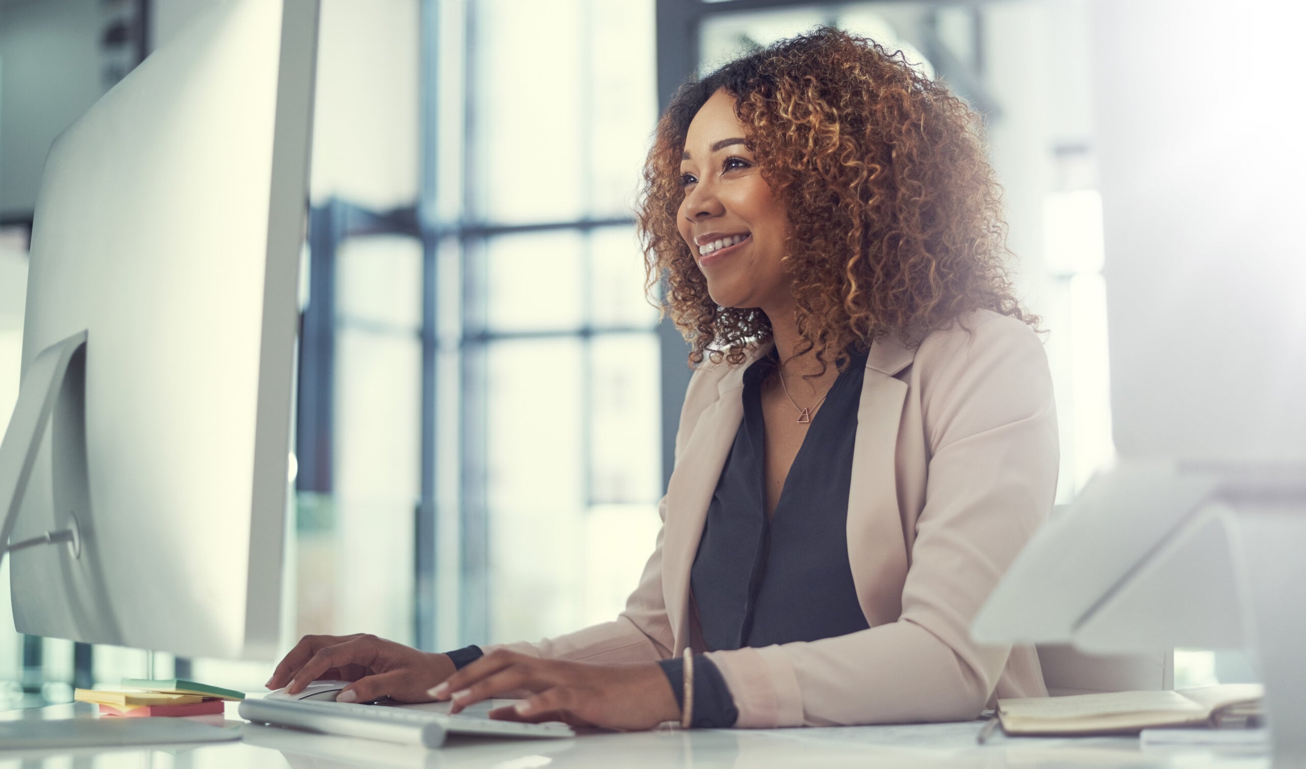Smiling woman works at computer in office